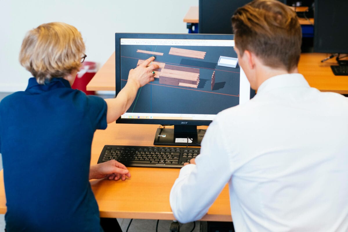 Ausbilderin erklärt einem Auszubildenden am Monitor eine 3D-Konstruktion in der Tischlerei